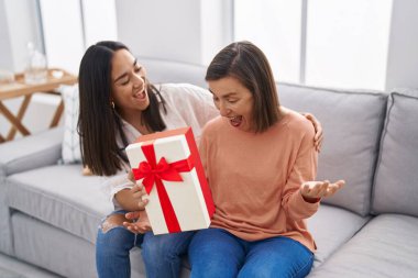 İki kadın anne ve kız evde hediyeyle sürpriz yapıyorlar.