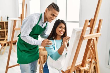 Resim stüdyosunda gülümseyen genç Latin ressam çift.