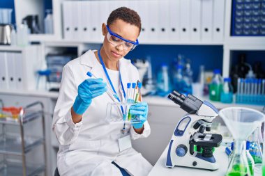 Laboratuvarda test tüpleri tutan Afrikalı Amerikalı kadın bilim adamı.