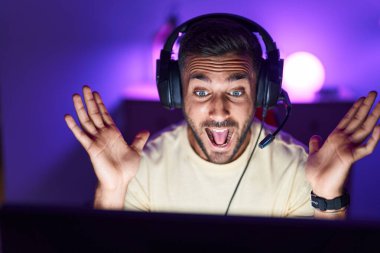 Oyun odasında İspanyol asıllı genç adam video oyunu oynuyor.