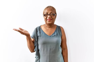 Tecrit edilmiş arka planda duran gözlüklü, olgun İspanyol bir kadın. Gülümsüyor, avucunun içi gibi kameraya bakıyor.. 