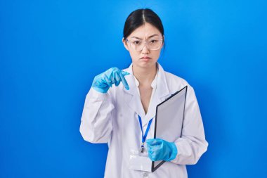 Laboratuvarda çalışan Çinli genç bir kadın üzgün ve üzgün görünüyor. Mutsuz ve depresif bir şekilde yönünü gösteriyor.. 