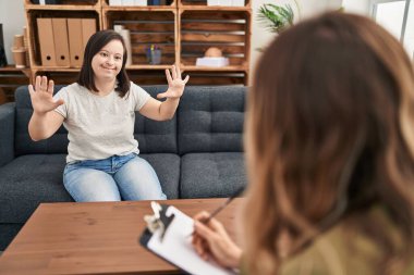 Down sendromlu İspanyol kız terapi yapıyor ve onuncu parmaklarını gösterip işaret ederken kendine güvenen ve mutlu gülümseyen.. 