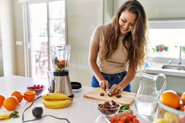 Genç ve güzel İspanyol kadın mutfakta sebze suyu ve blender karışımı hazırlıyor.