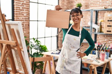 Güzel İspanyol kadın ressam gülümsüyor sanat stüdyosunda kendine güvenen bir çanta tutuyor.