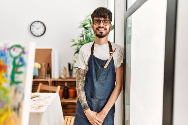 Genç İspanyol ressam mutlu bir şekilde resim stüdyosunda duruyor..