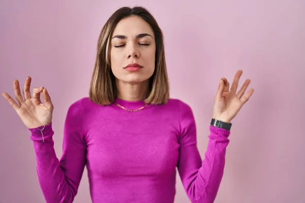 ピンクの背景の上に立つヒスパニック系の女性がリラックスし 目を閉じて指で瞑想ジェスチャーを行う笑顔 ヨガのコンセプト — ストック写真