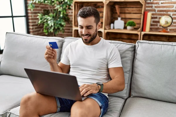 Молодий Іспаномовний Чоловік Посміхається Впевнено Використовуючи Ноутбук Кредитну Картку Вдома — стокове фото