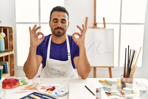年轻的他的恐慌男子在艺术工作室用粉刷的脸 放松和微笑与眼睛关闭做冥想手势用手指 瑜伽概念 — 图库照片