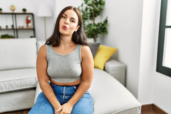 Jovem Morena Sentada Sofá Casa Olhando Para Câmera Soprando Beijo — Fotografia de Stock