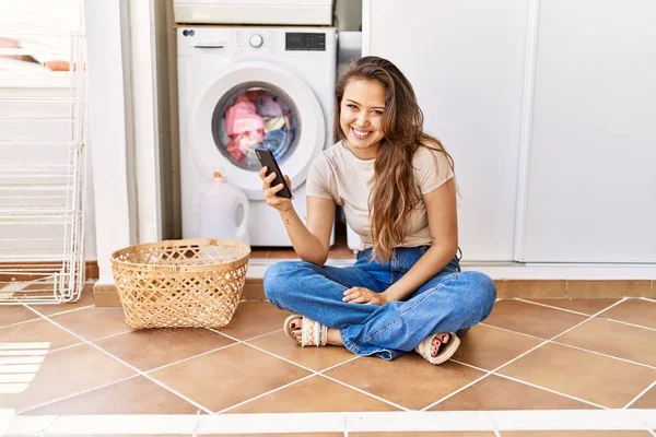 Ung Latinamerikansk Flicka Med Smartphone Väntar Tvättmaskin Hemma — Stockfoto