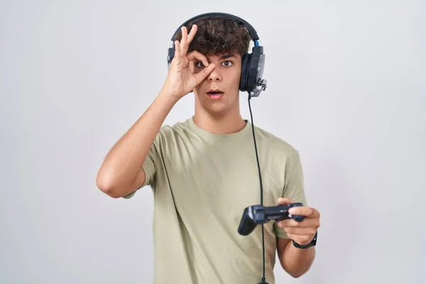 Hispanic Teenager Playing Video Game Holding Controller Doing Gesture Shocked — Stock Photo, Image