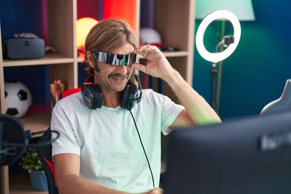 年轻的金发男子在游戏室用虚拟现实眼镜玩电子游戏 — 图库照片