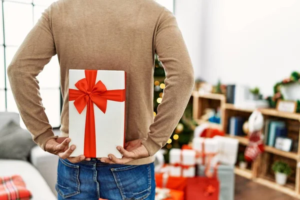 Young Hispanic Man Holding Christmas Gift His Back Home —  Fotos de Stock
