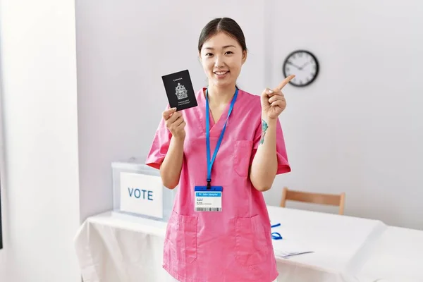 Молодая Женщина Медсестра Азии Выборах Держащая Канадский Паспорт Улыбаясь Указывая — стоковое фото