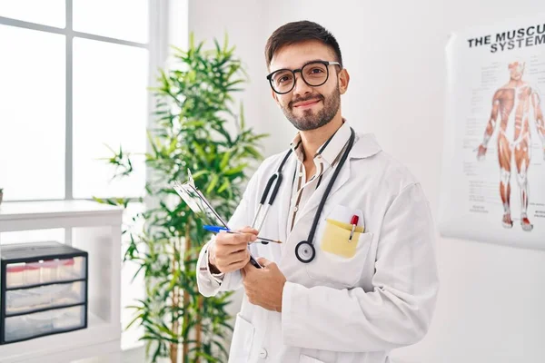 Junger Hispanischer Arzt Lächelt Selbstbewusst Und Hält Klemmbrett Klinik — Stockfoto