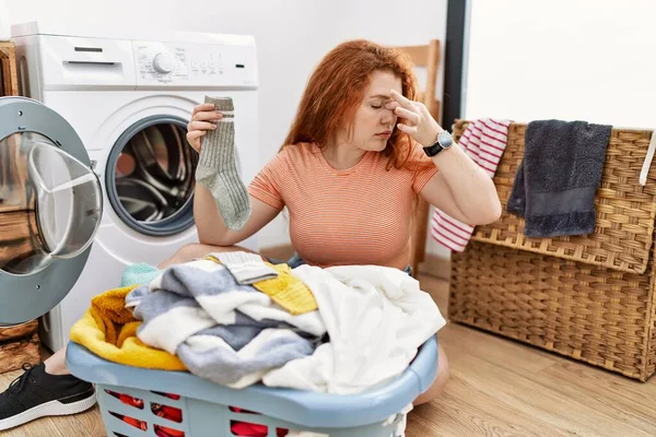 若い赤毛の女性は 疲れ鼻や目をこすり洗濯機に汚れた洗濯を入れて疲労や頭痛を感じます ストレスとフラストレーションの概念 — ストック写真