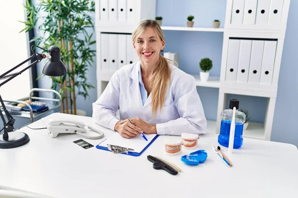 Young Blonde Woman Wearing Dentist Uniform Sitting Table Clinic — Stock fotografie