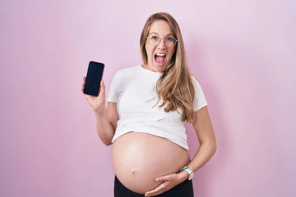 Mladá Těhotná Žena Ukazuje Břicho Drží Smartphone Slaví Šílený Ohromen — Stock fotografie