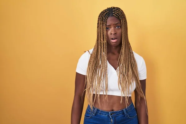 Африканская Американка Плетеными Волосами Стоящая Желтом Фоне Шоковом Лице Выглядящая — стоковое фото