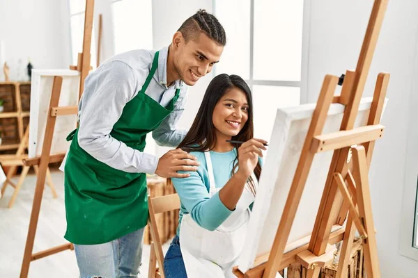 Resim stüdyosunda gülümseyen genç Latin ressam çift.