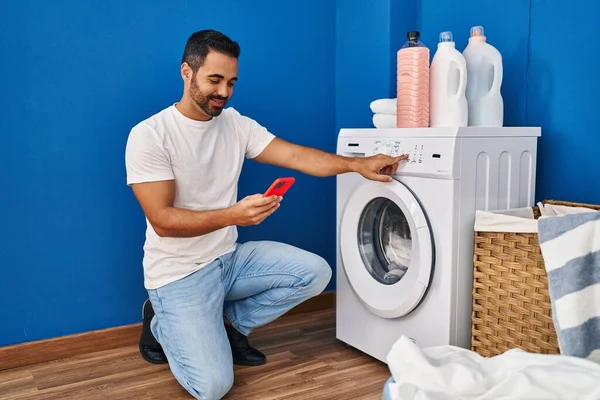 Ung Latinamerikan Man Slå Tvättmaskin Med Hjälp Smartphone Tvättstuga — Stockfoto