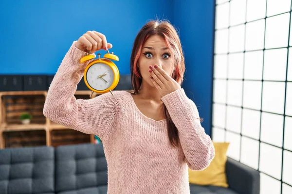 Young Caucasian Woman Holding Alarm Clock Covering Mouth Hand Shocked — Stock Photo, Image