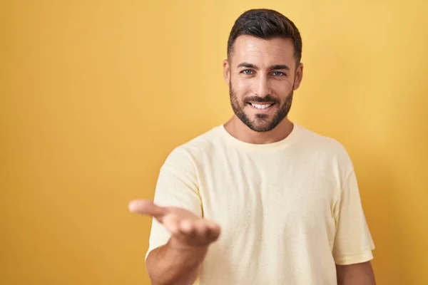 Hombre Hispano Guapo Pie Sobre Fondo Amarillo Sonriente Alegre Ofreciendo — Foto de Stock