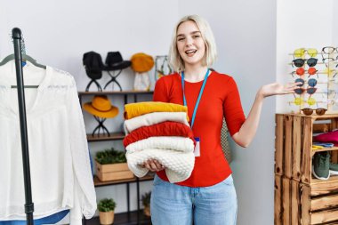 Perakende satış mağazasında yönetici olarak çalışan genç beyaz kadın başarıyı mutlu bir gülümsemeyle ve el kaldırarak kazanan ifadeyle kutluyor. 