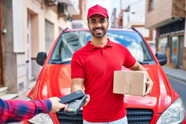 Genç İspanyol kurye verafon ve akıllı telefonla caddede şarj oluyor.