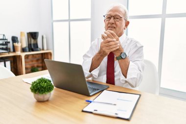 Ofiste çalışan kıdemli bir adam bilgisayar kullanıyor. Ellerinde ve parmaklarında ağrı var. Eklem iltihabı. 