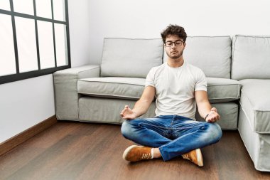 Genç İspanyol adam evde yoga egzersizi yapıyor.