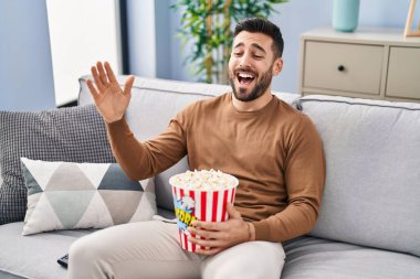 Evdeki kanepede oturmuş film izleyen İspanyol genç adam.