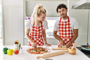 Mutfakta İtalyan pizzası pişiren gülümseyen genç çift..