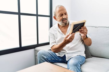 Yaşlı, gri saçlı, gülümseyen, kendine güvenen bir adam.