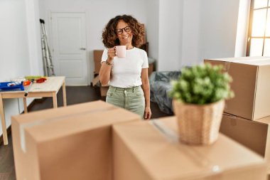 Orta yaşlı, kendine güvenen, yeni evinde kahve içen İspanyol bir kadın.