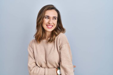 İzole edilmiş arka planda duran genç bir kadın yüzünde gülümsemeyle, doğal bir ifadeyle yan yana bakıyor. Kendinden emin gülen. 