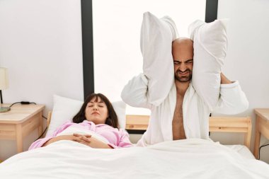 Yatakta horlayan bir kadın varken, kulaklarında yastıkla İspanyol bir adam sinirlendi..