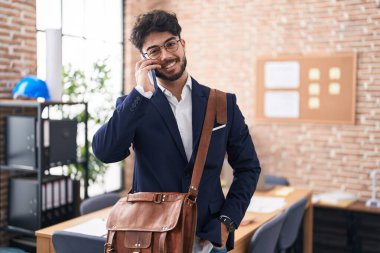 Genç İspanyol iş adamı ofiste akıllı telefondan konuşuyor.