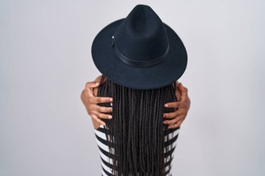 Saçları örgülü, şapka takan, güneş gözlüklü, mutlu ve olumlu bir şekilde sarılan genç bir Afrikalı Amerikalı. Sevgi ve özgüven. 