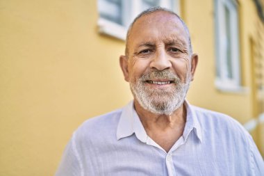 Kıdemli adam sokakta kendinden emin gülümsüyor.