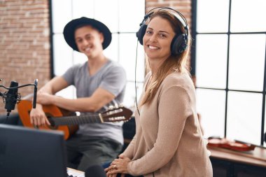 Erkek ve kadın müzisyenler müzik stüdyosunda klasik gitar çalıyor.