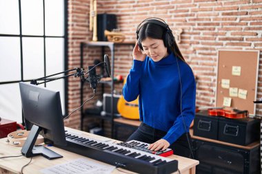 Çinli kadın müzisyen müzik stüdyosunda DJ 'lik yapıyor.