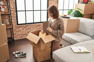 Beyaz bir kadın yeni evinde kendine güvenen bir paket paketliyor.