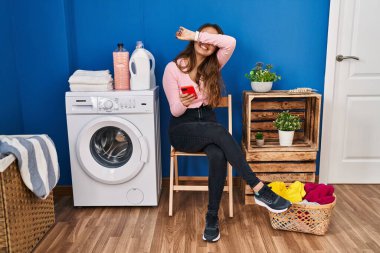 Genç İspanyol kadın çamaşırlarını yıkamak için bekliyor. Akıllı telefon kullanıyor. Gülümsüyor, gülümsüyor. Şaşırdım ve çıktım. 