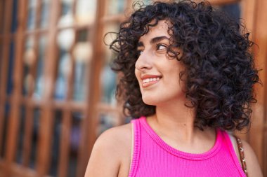 Orta Doğulu genç bir kadın oyun odasında kendine güvenen bir şekilde yan tarafa bakıyor.