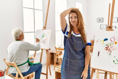 Sanat atölyesinde önlük giyen İspanyol kadın soru sorup şaşırıyor. Şüpheyle kararsız, kafa kafaya düşünerek. Düşünceli kavram. 