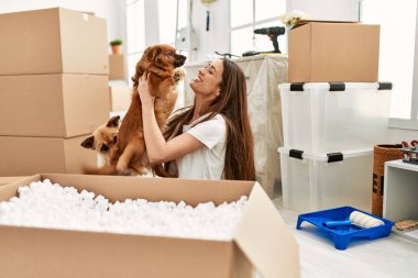 Genç İspanyol kadın gülümsüyor. Kendine güvenen, kucaklayan köpek yeni evinde yerde oturuyor.