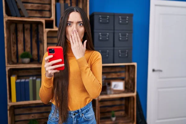 Jovem Morena Usando Smartphone Cobrindo Boca Com Mão Chocada Com — Fotografia de Stock