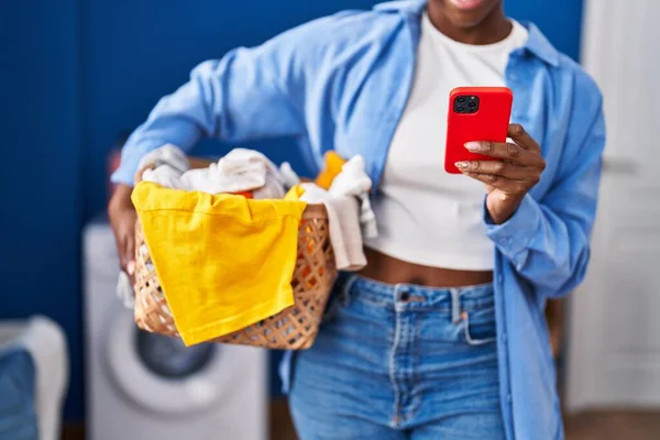 Afroamerykanka Trzyma Kosz Ubraniami Pomocą Smartfona Pralni — Zdjęcie stockowe
